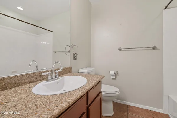 a bathroom with a granite countertop sink a toilet and a mirror