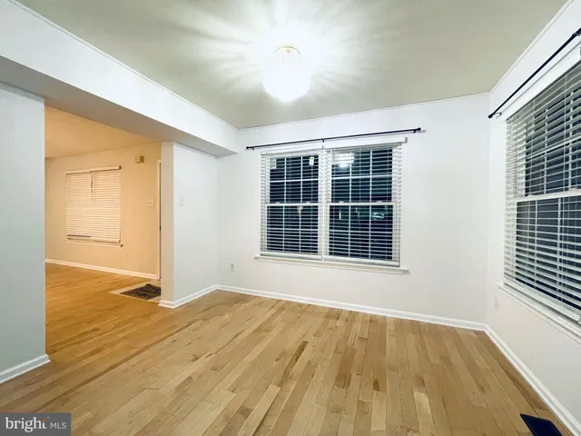 a view of an empty room with a window and wooden floor