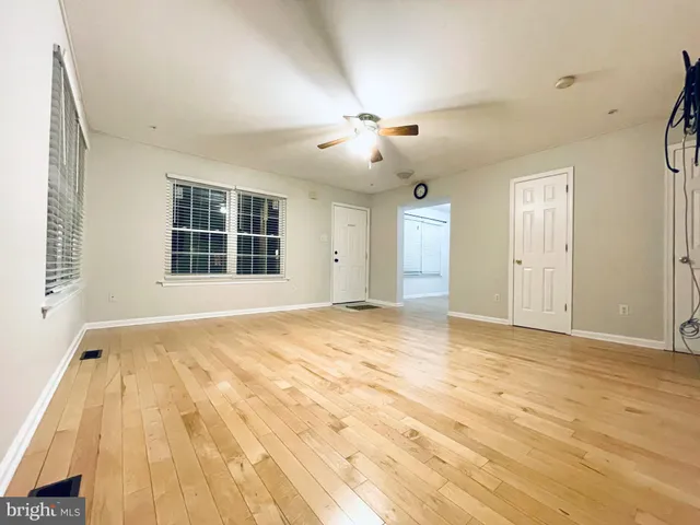 a view of an empty room with chandelier fan and windows