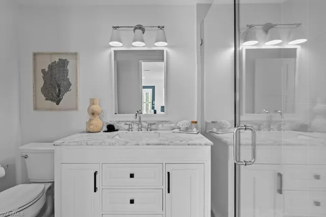 a bathroom with a granite countertop sink vanity mirror and toilet