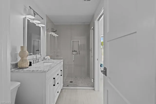 a bathroom with a granite countertop sink two mirror and shower