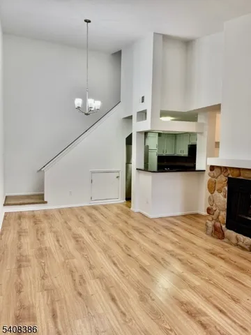 a view of empty room with wooden floor and kitchen view