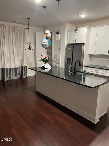a kitchen with kitchen island granite countertop a sink cabinets and wooden floor