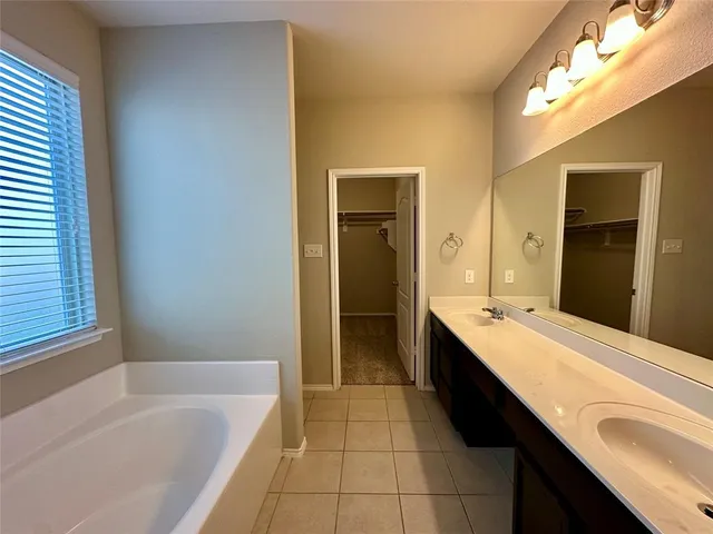 a bathroom with a tub sink shower and two mirror