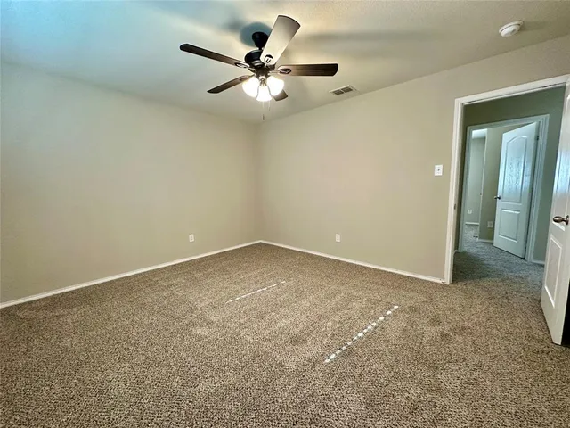 an empty room with a chandelier fan and windows