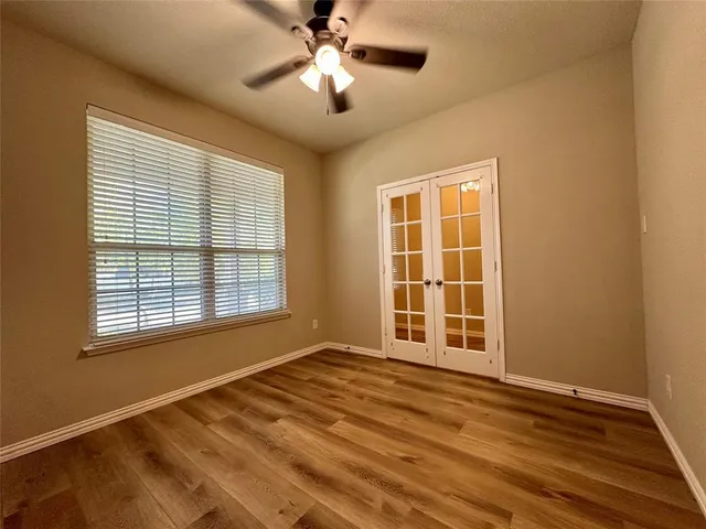 a view of an empty room with a window and wooden floor