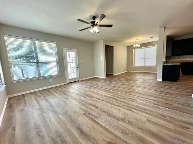 a view of an empty room with a window and wooden floor