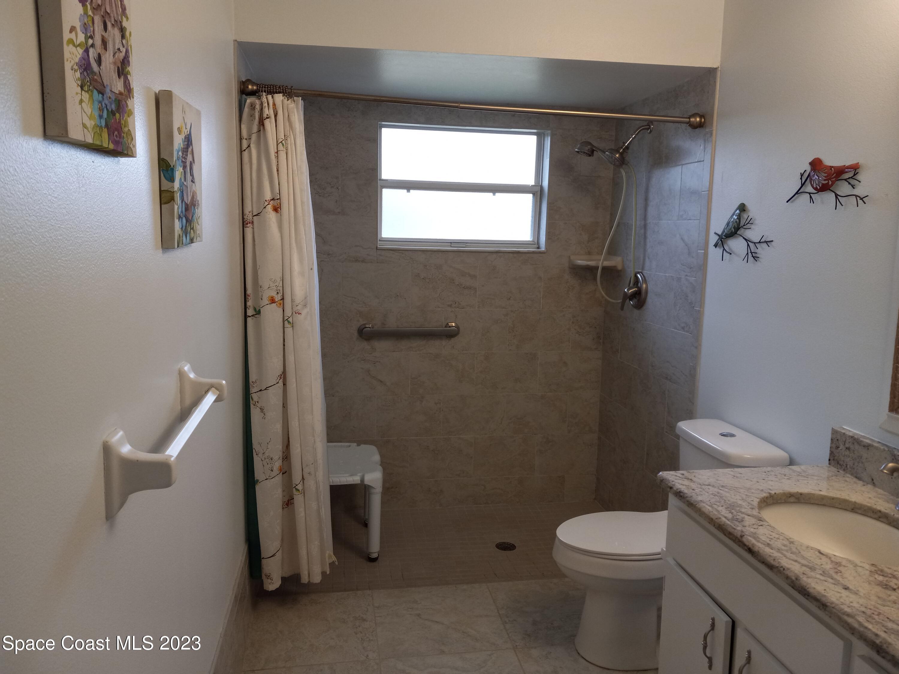 5166 Arlington Road Cocoa, FL 32927 - Photo 18 of 25 a bathroom with a granite countertop toilet a sink and a shower