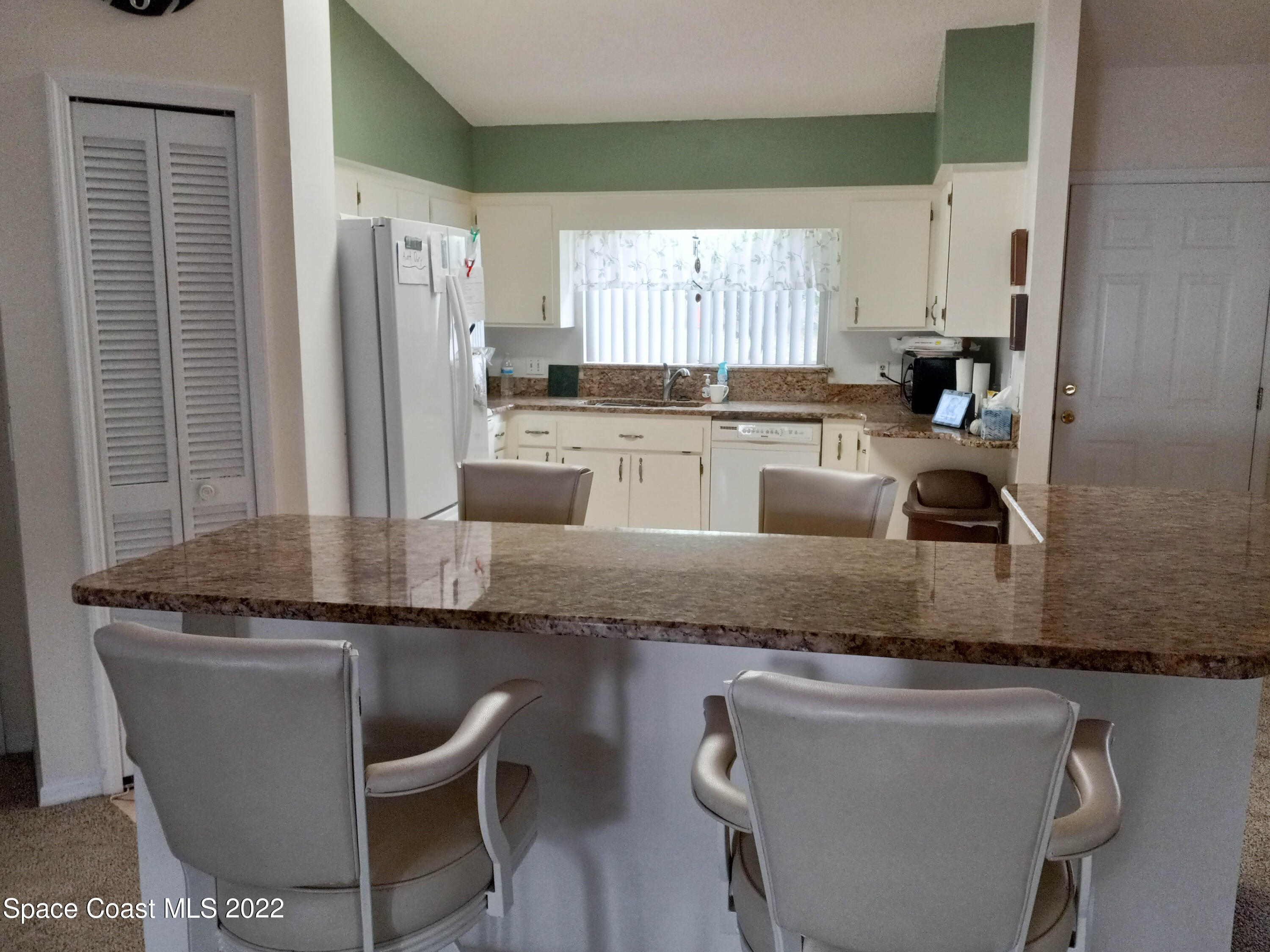 5166 Arlington Road Cocoa, FL 32927 - Photo 7 of 25 a kitchen with granite countertop kitchen island stainless steel appliances a refrigerator a sink and white cabinets