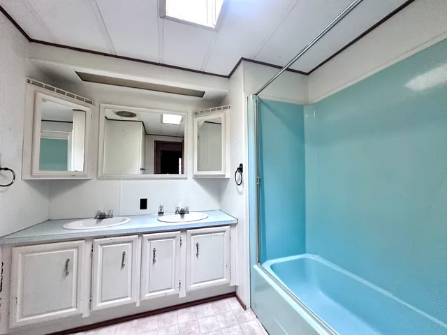 a bathroom with a tub a sink and mirror