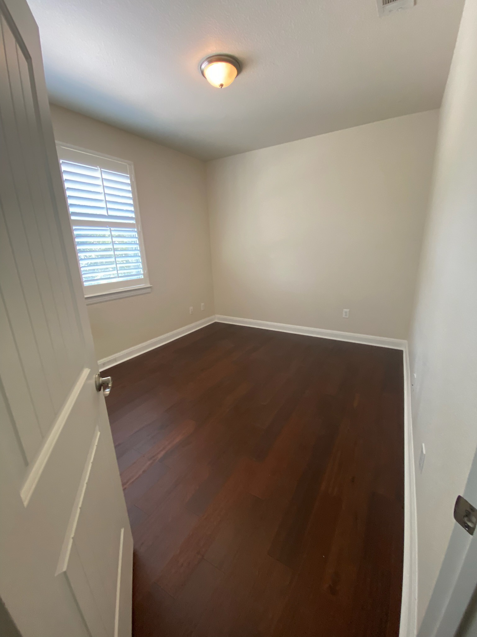 6708 Menchaca Road, Unit 25 Austin, TX 78745 - Photo 5 of 8 Rich hardwood flooring anchors this versatile room featuring plantation shutters and clean trim details.
