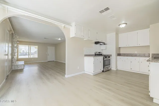 a view of kitchen with granite countertop white cabinets and stainless steel appliances