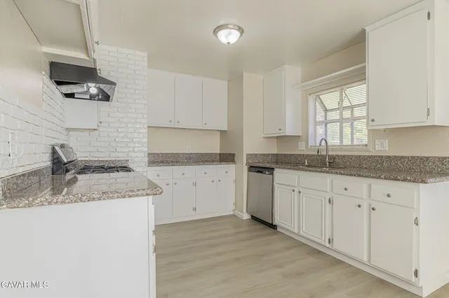 a kitchen with granite countertop cabinets stainless steel appliances a sink and a window