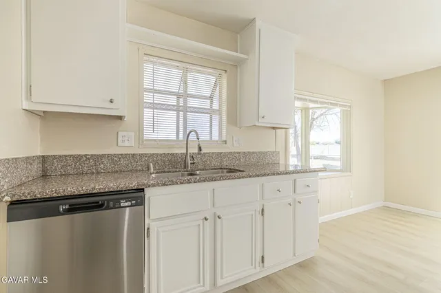 a kitchen with granite countertop white cabinets and a window