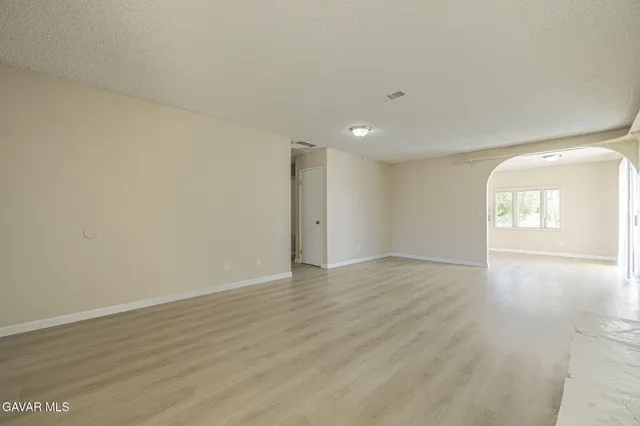 a view of an empty room with wooden floor and window