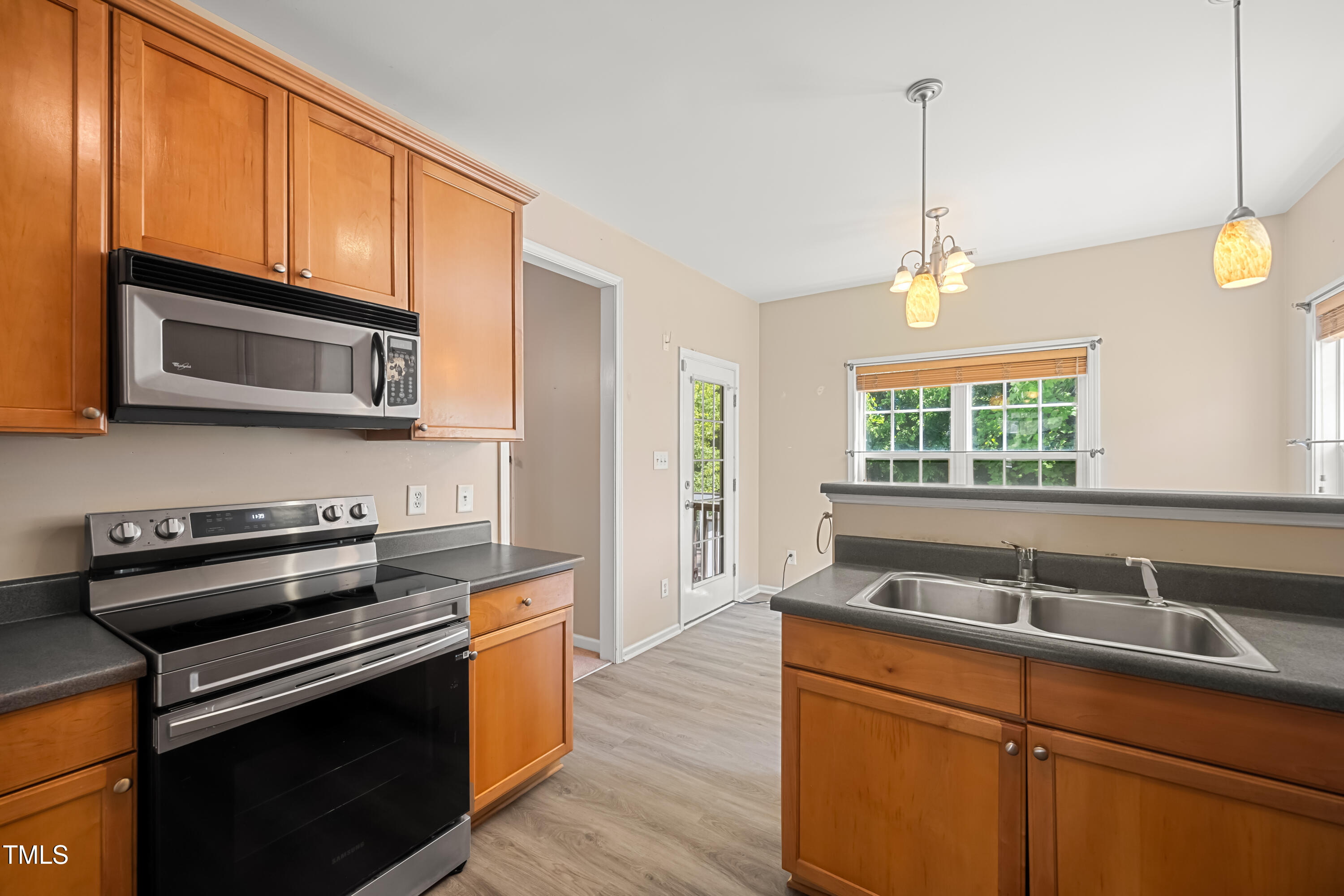 5865 Forest Point Road Raleigh, NC 27610 - Photo 11 of 37 a kitchen with stainless steel appliances granite countertop a sink a stove a microwave and wooden floors