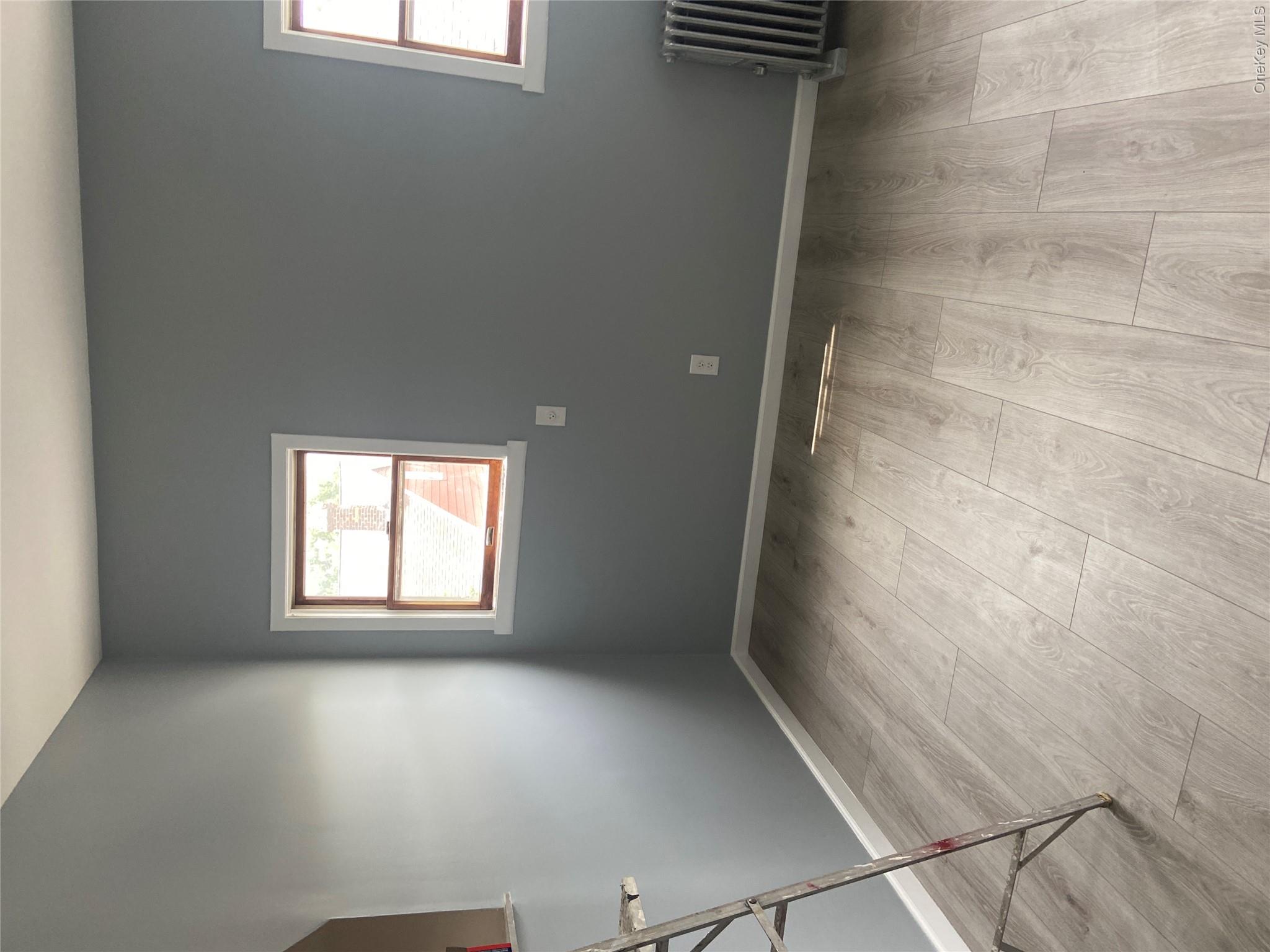 85-15 85th Street, Unit 2 Queens, NY 11421 - Photo 5 of 22 Light gray wood-finish flooring complements the neutral wall color
