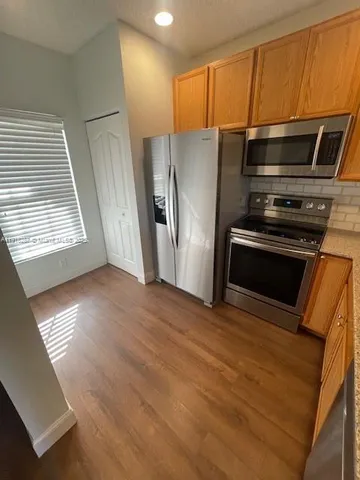 a view of kitchen with stainless steel appliances wooden floor and window