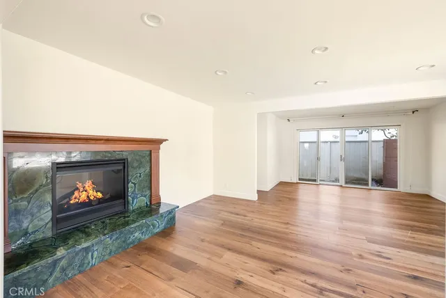 a view of an empty room with wooden floor fireplace and a window
