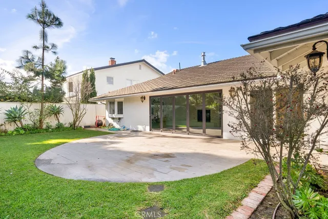 a view of a white house next to a yard with big trees
