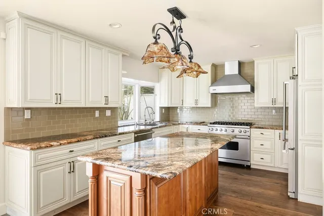 a kitchen with kitchen island granite countertop a sink a counter space appliances and cabinets