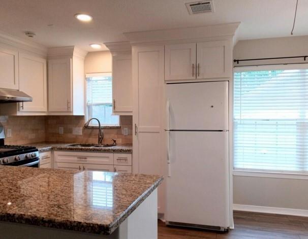 a kitchen with kitchen island granite countertop white cabinets and refrigerator