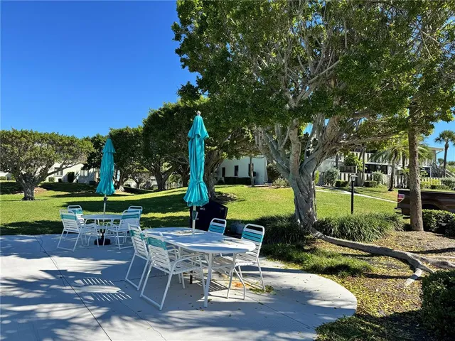a view of a patio with table and chairs potted plants and a large tree
