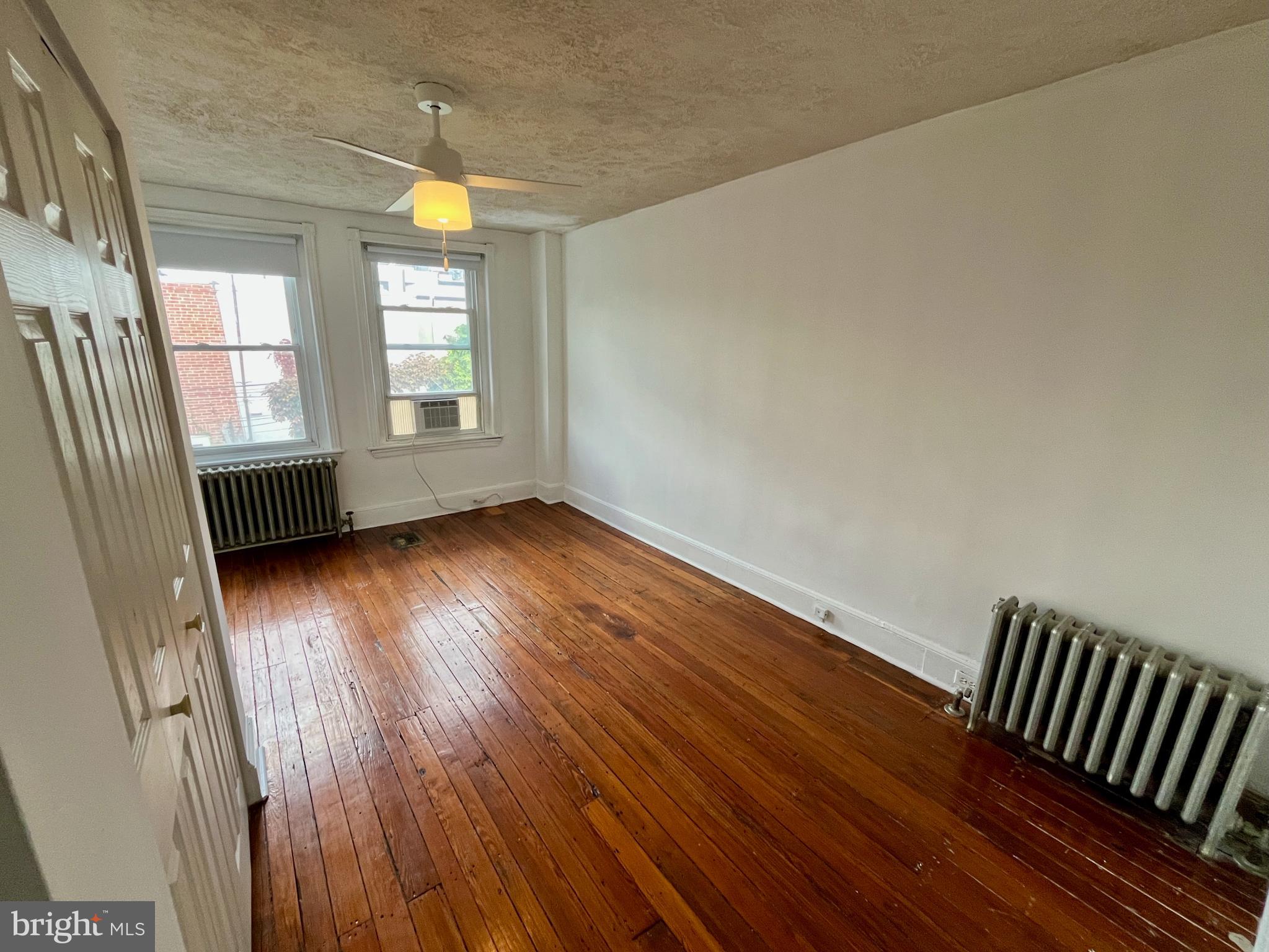 1217 Wharton Street Philadelphia, PA 19147 - Photo 18 of 27 an empty room with wooden floor and windows