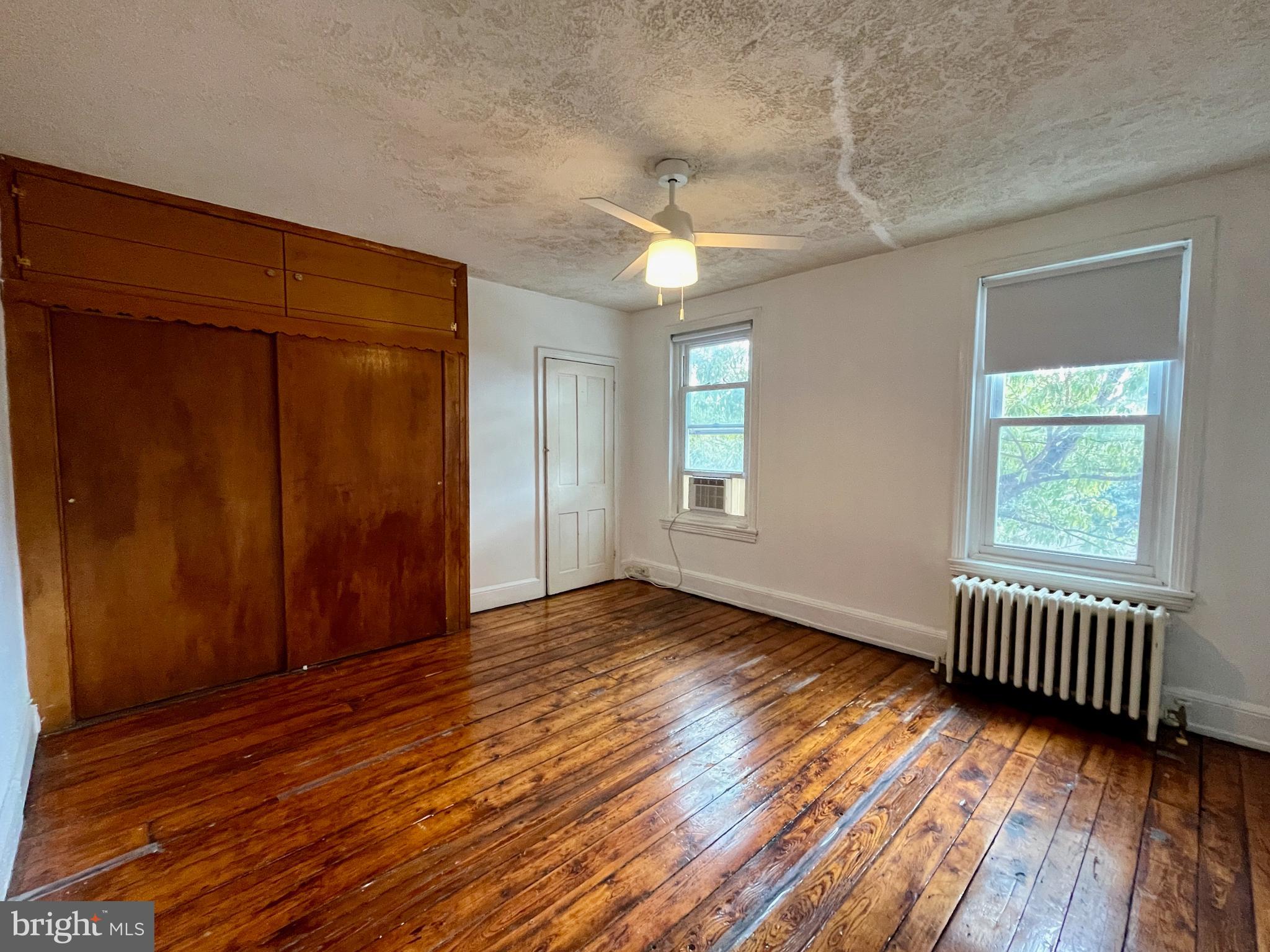 1217 Wharton Street Philadelphia, PA 19147 - Photo 22 of 27 an empty room with wooden floor and windows with curtains