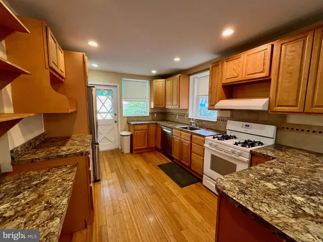 a kitchen with stainless steel appliances granite countertop wooden cabinets a stove top oven a sink and dishwasher