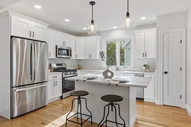 a kitchen with kitchen island white cabinets and stainless steel appliances