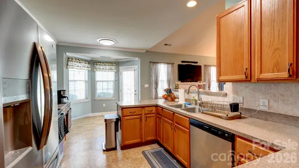 a kitchen with stainless steel appliances a sink dishwasher a refrigerator and a stove with wooden floor