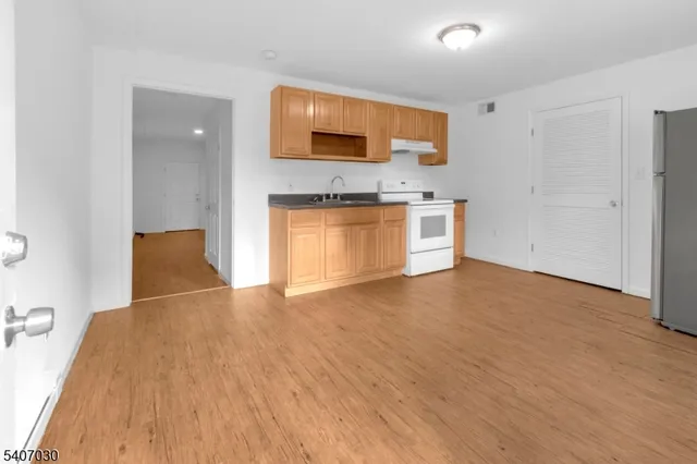a view of empty room with a kitchen and wooden floor