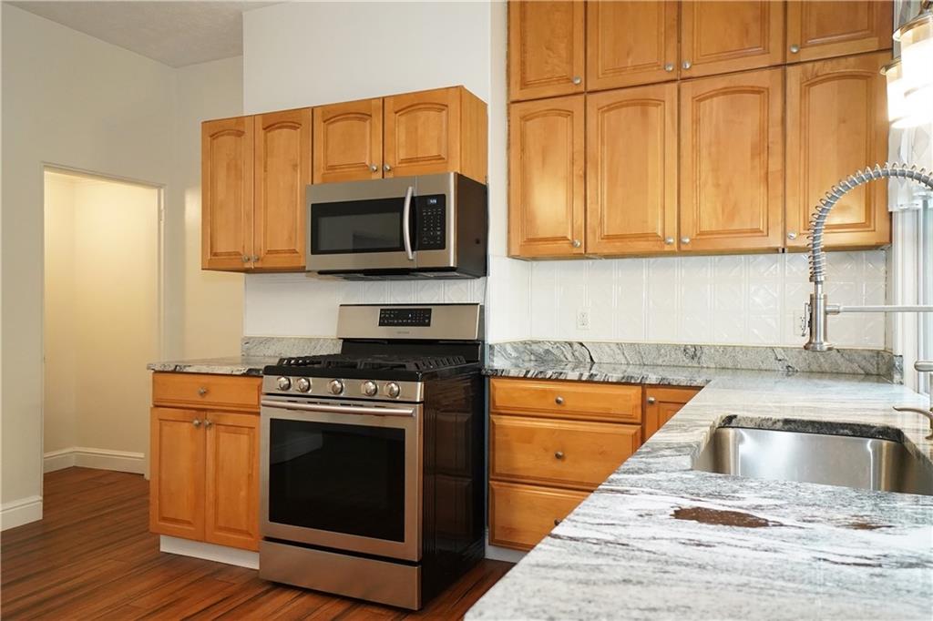 5266 Natrona Way Pittsburgh, PA 15201 - Photo 6 of 13 a kitchen with stainless steel appliances granite countertop a stove a microwave and a sink