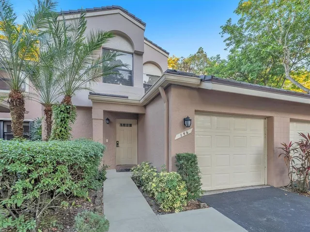 a view of a white house with large windows and a small yard