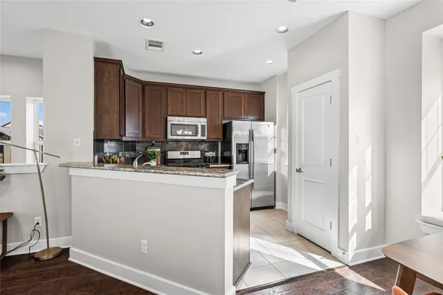 a kitchen with stainless steel appliances granite countertop a refrigerator and a stove top oven