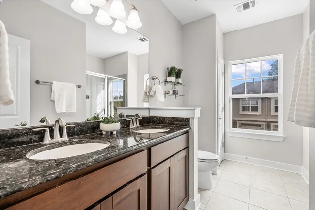 a bathroom with a granite countertop sink a toilet and a mirror