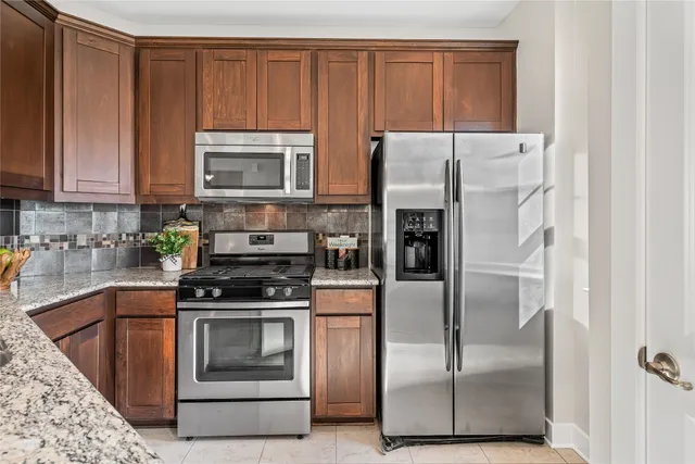 a kitchen with granite countertop a refrigerator stove and microwave