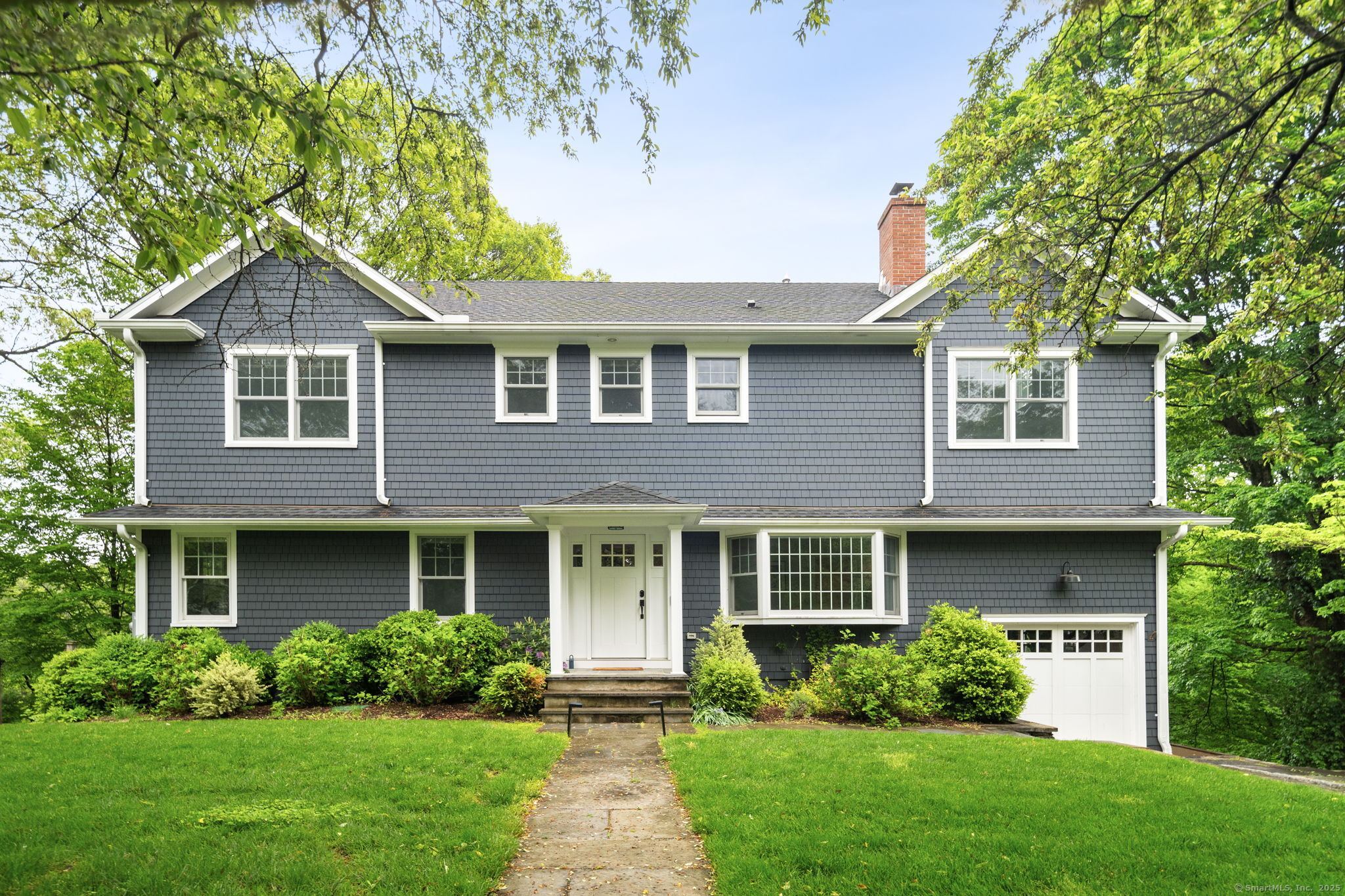 a front view of a house with a yard and green space