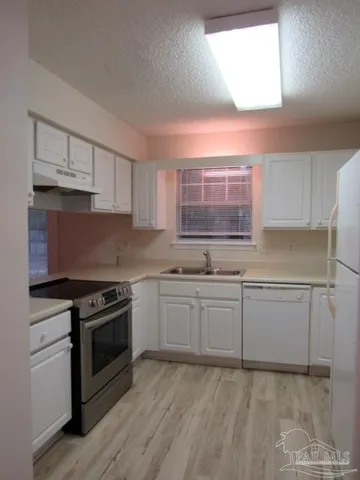 a kitchen with granite countertop white cabinets and white appliances