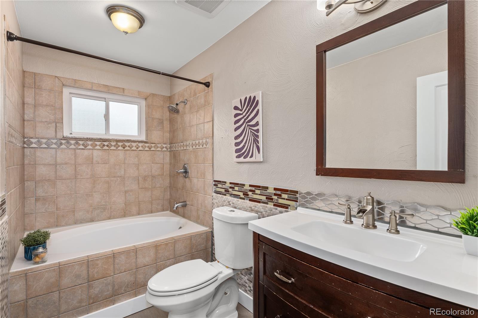 3920 Collins Street Castle Rock, CO 80108 - Photo 24 of 40 a bathroom with a granite countertop sink a toilet a mirror a bathtub and shower