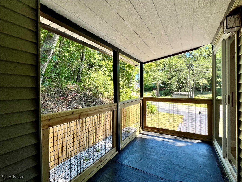 Unfurnished sunroom featuring vaulted ceiling and a balcony