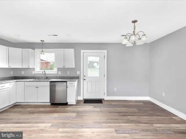 a view of a kitchen with granite countertop stainless steel appliances cabinets a sink and a counter top space