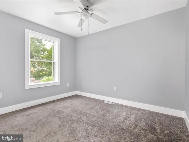 an empty room with a window and a fan