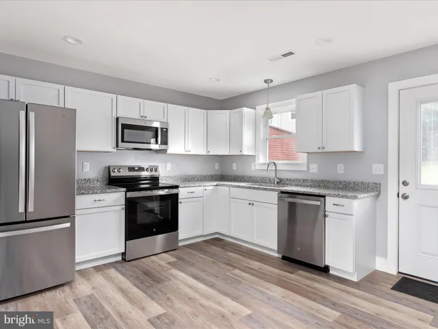 a kitchen with granite countertop a refrigerator stove and microwave