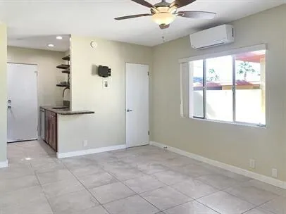 a view of an empty room with window and chandelier fan