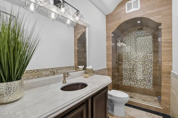 a bathroom with a granite countertop sink a toilet and shower