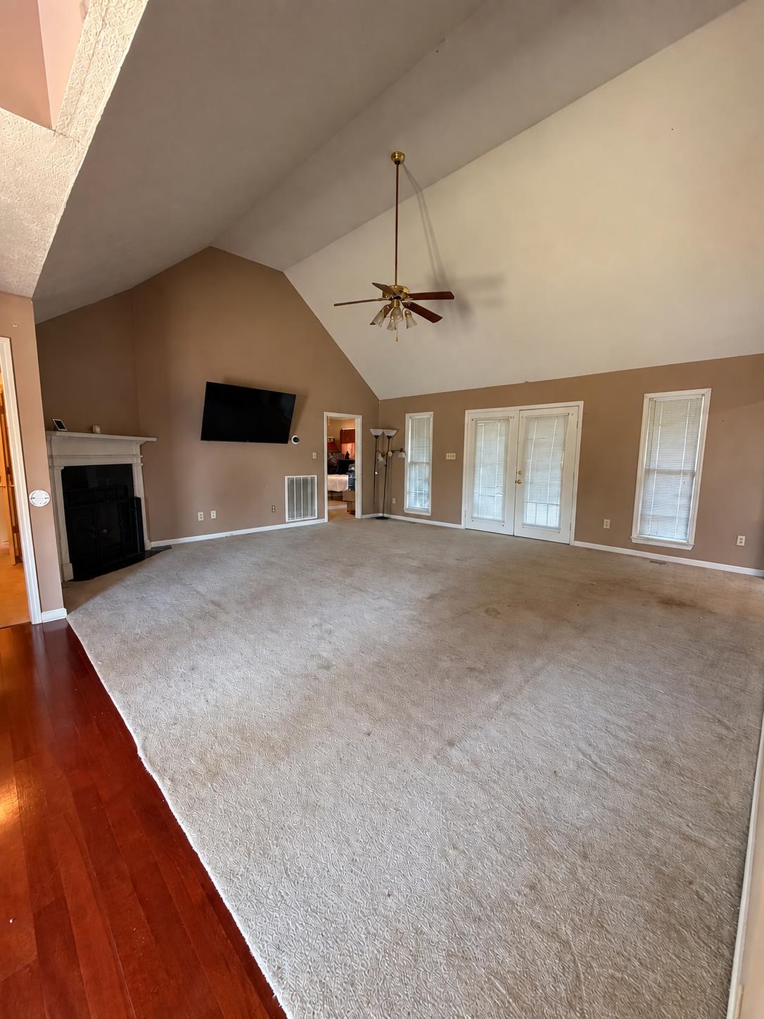 741 Dancer Road Selmer, TN 38375 - Photo 2 of 30 Vaulted ceilings featuring a ceiling fan, a fireplace with a white mantel, and double doors providing access to the sunroom.