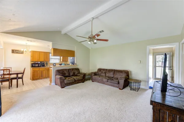 a living room with furniture kitchen view and a chandelier