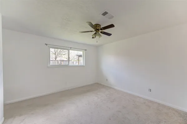 an empty room with windows and fan